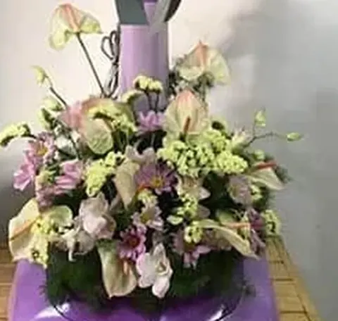 ช่อหน้าวัวชมพูปลายเขียว ดอกเล็กสีเขียวมะนาว และดอกชมพูม่วงบนฐานพัดลมสีม่วงอ่อน